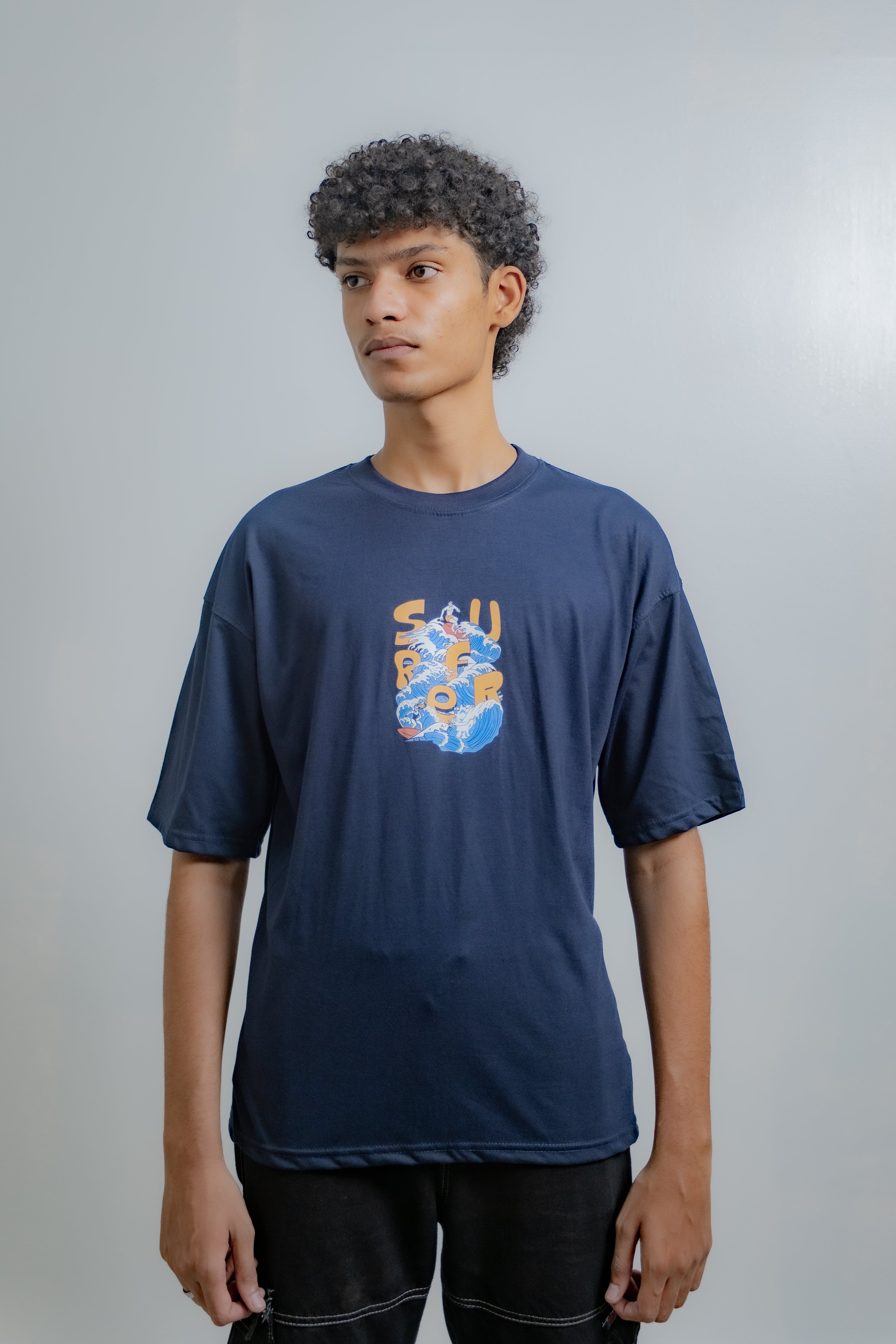 Person wearing a navy blue t-shirt with a colorful graphic design on a plain background