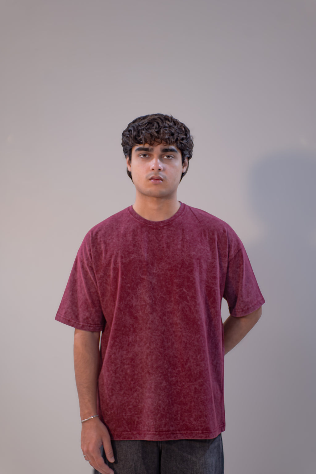 Person wearing a maroon t-shirt against a plain background