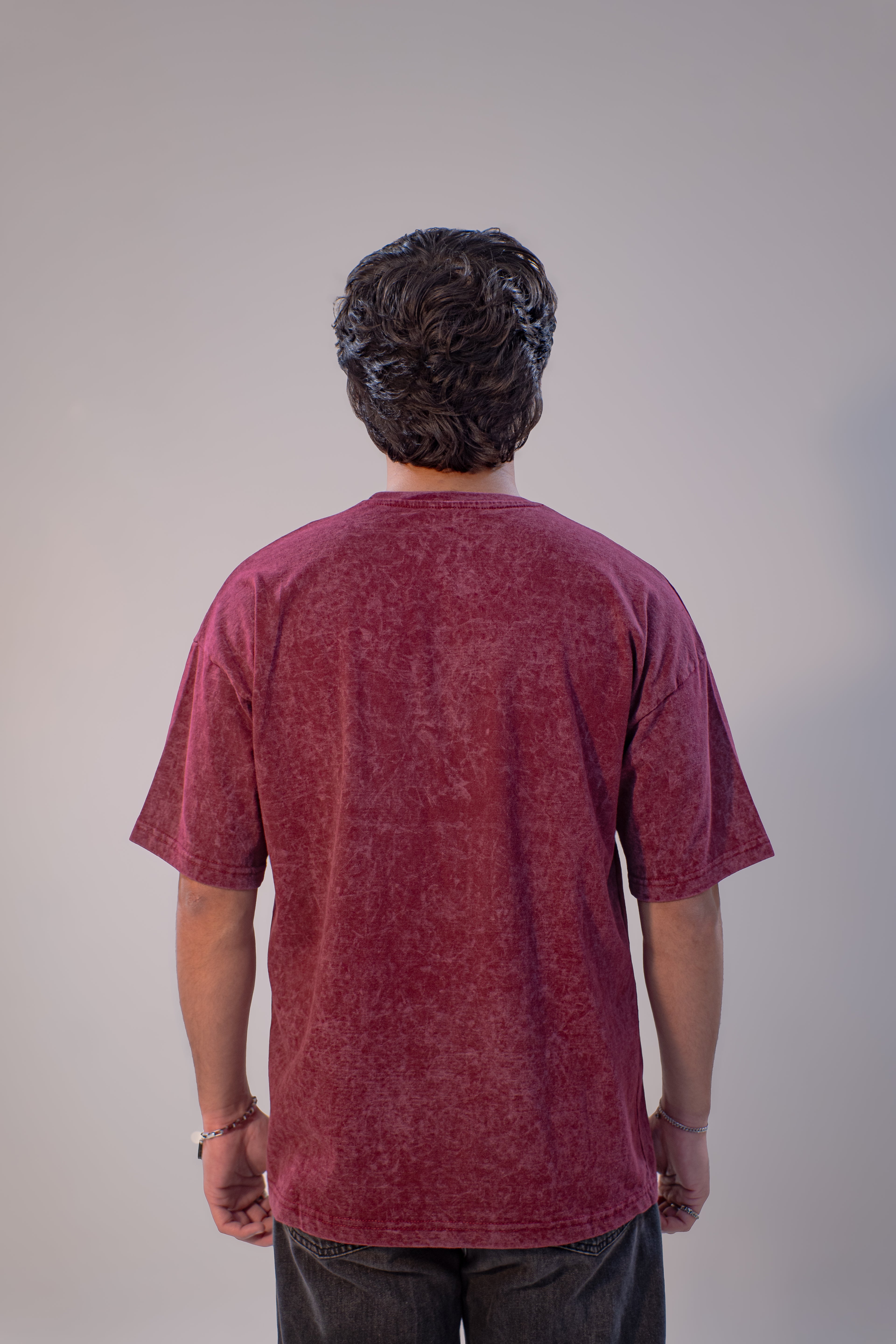 Person wearing a maroon t-shirt against a plain background