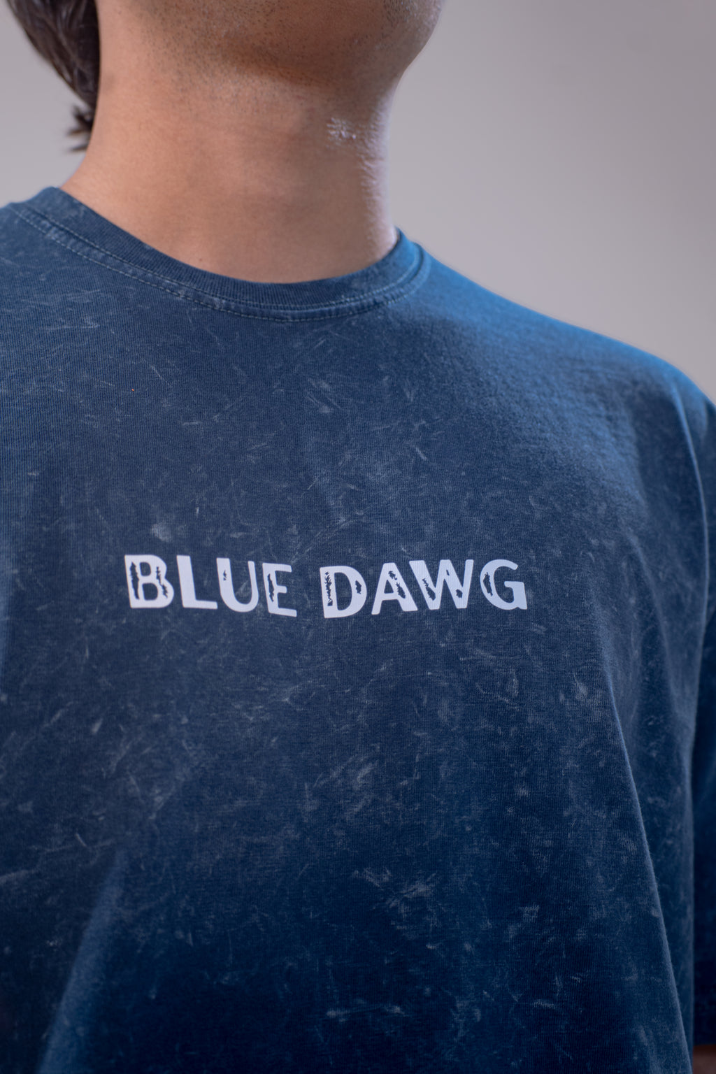 Person wearing a blue t-shirt with 'BLUE DAWG' text on a plain background