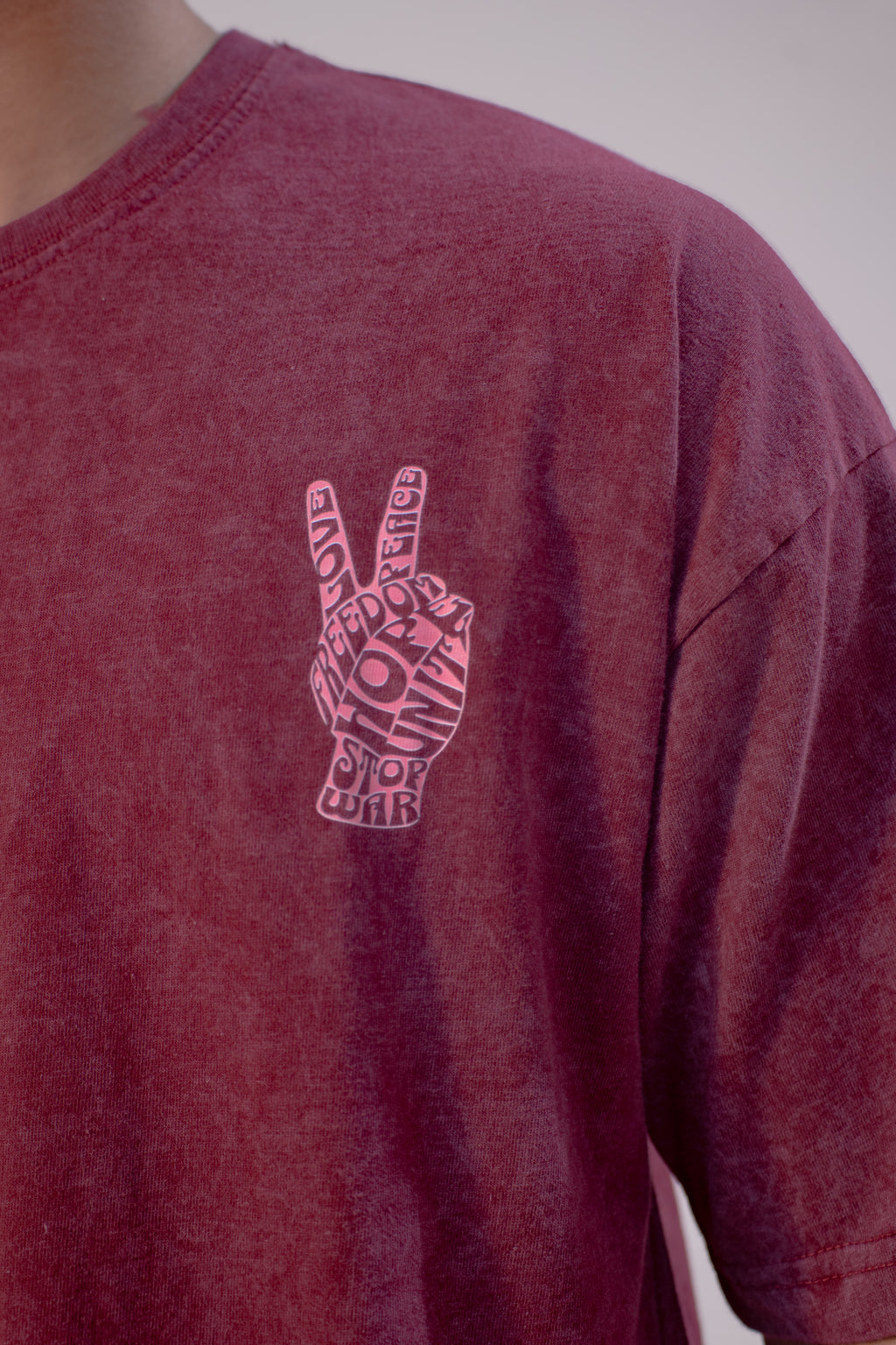 Maroon t-shirt with a peace sign design on a plain background