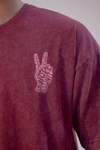 Maroon t-shirt with a peace sign design on a plain background
