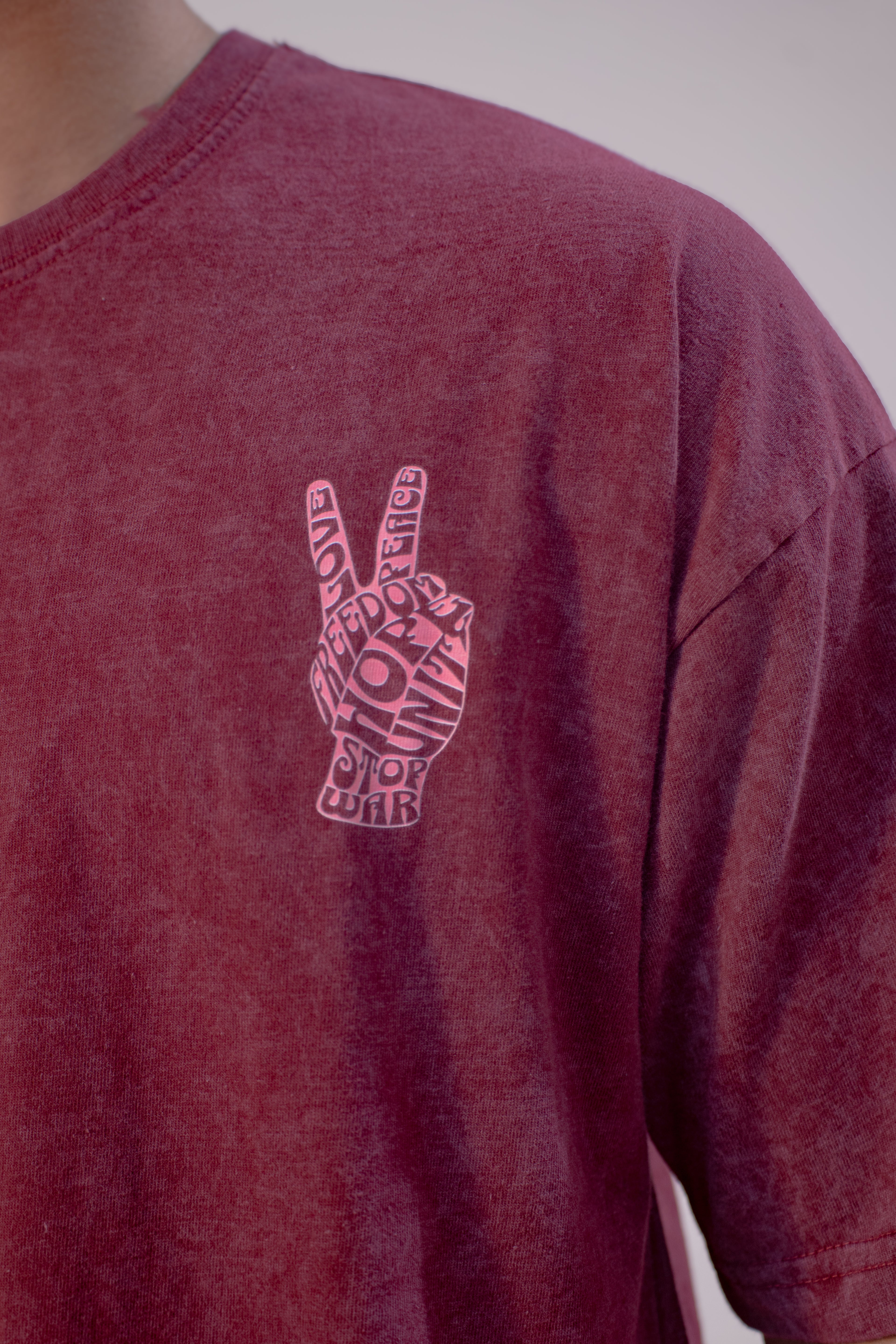 Maroon t-shirt with a peace sign design on a plain background
